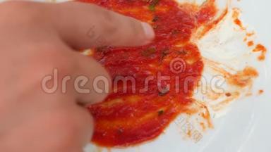 用番茄酱的残留物清空<strong>脏盘子</strong>。 男人`手在番茄酱的残骸上画着微笑。 4k，慢镜头